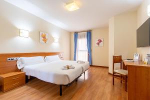 una camera d'albergo con letto e scrivania di Hotel Zaravencia Plaza Mayor by InsideHome a Toro