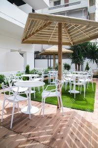 a group of white tables and chairs under a wooden umbrella at Celia Residence in Athens