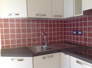 a kitchen with a sink and red tiles on the wall at Italian Breeze in Soverato Marina