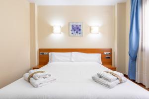 1 dormitorio con 2 toallas en una cama blanca en Hotel Zaravencia Plaza Mayor by InsideHome, en Toro