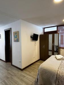 a bedroom with a bed and a tv on a wall at Mamitas House! Mini Suit Privada Junto al Metro de Quito in Quito