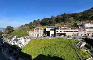 a town with a green hill with houses and cars at La Terraza del Àtico con parking incluido in Vigo