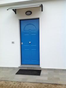 eine blaue Tür an der Seite einer weißen Wand in der Unterkunft Italian Breeze in Soverato Marina
