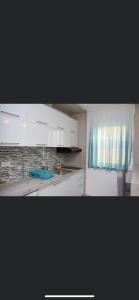 a kitchen with white cabinets and a blue curtain at Romantika 3 in Ostrovo