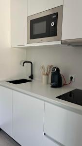 uma cozinha branca com um micro-ondas e um lavatório em La Terraza del Àtico em Vigo