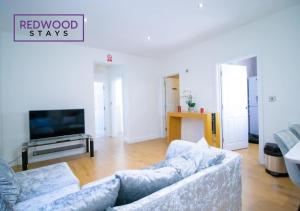 a living room with a couch and a tv at Spacious Serviced Apartment for Contractors and Families, FREE WiFi & Netflix by REDWOOD STAYS in Farnborough