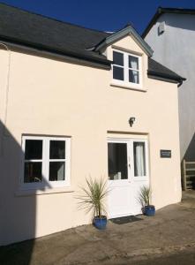 a white house with two potted plants in front of it at Courtyard Cottage - Grade II listed - Barnstaple in Barnstaple