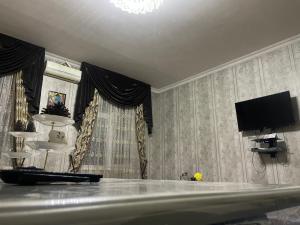 un soggiorno con TV e tende di Cozy apartment a Samarkand