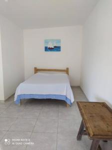 1 dormitorio con cama y mesa de madera en COMPLEJO PONTA das BRILLES DUPLEX en Nísia Floresta