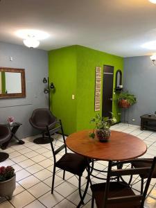 Zimmer mit einem Tisch, Stühlen und einer grünen Wand in der Unterkunft Caza en zona residencial in Uruapan del Progreso