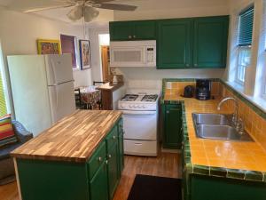cocina con armarios verdes y nevera blanca en Green garden view, en Nueva Orleans