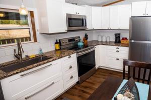 uma cozinha com armários brancos e electrodomésticos de aço inoxidável em Home away from Home at Beyonder Getaway SH em Ankeny