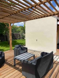 um deque de madeira com 3 cadeiras e uma pérgola de madeira em Petite maison avec jardin au calme em Floirac