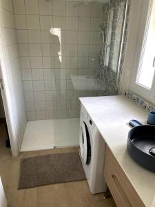 uma casa de banho com um chuveiro e uma máquina de lavar roupa em Petite maison avec jardin au calme em Floirac
