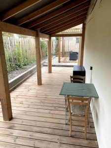 um deque de madeira com uma mesa verde e uma cadeira em Petite maison avec jardin au calme em Floirac