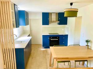 uma cozinha com armários azuis e uma mesa de madeira em Petite maison avec jardin au calme em Floirac