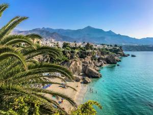 a beach with palm trees and people on the beach at Plaza de España Boutique Apartment in Nerja