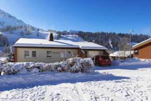 ein schneebedecktes Haus mit einem Auto vor dem Haus in der Unterkunft Familienfreundliche Ferienwohnung mit Spielwiese Haus Reanchme Parterre - b48833 in Sörenberg