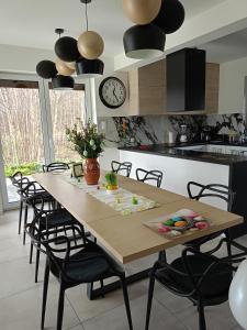 a kitchen with a wooden table with chairs and a clock at Willa w Brzozach Sznurki Spokojna 1 - Chmielno, Kaszuby, dom, jezioro in Chmielno