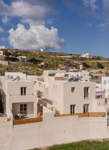 Blick auf ein weißes Gebäude mit einem Hügel im Hintergrund in der Unterkunft Sugarwhite Suites with Private not Heated Pool in Emporio