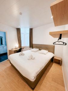 een slaapkamer met een groot bed met witte lakens bij Alpha Hotel in Oostende