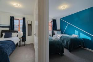 a bedroom with two beds and a blue wall at Spacious 5 rooms 6 beds in Banbury with Free Parking in Banbury