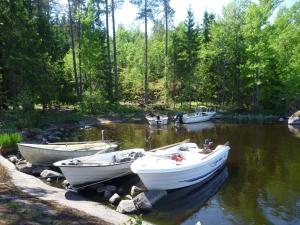 drie boten zijn aangemeerd op een rivier met bomen bij Brovillan in Lekeryd