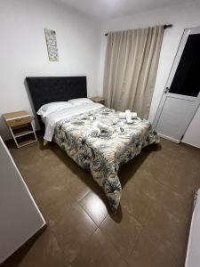 - une chambre avec un lit et une couverture fleurie dans l'établissement hospedaje LH E a 15 minutos del aeropuerto ezeiza, à Ezeiza