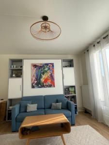 una sala de estar con un sofá azul y una pintura en Le Saint-Maurien en Saint-Maur-des-Fossés
