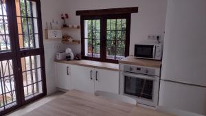 una cucina con armadietti bianchi e forno a microonde di Casa La Liebrecilla a Ríogordo