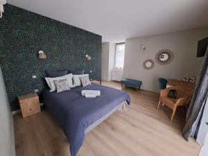 - une chambre avec un lit bleu et un mur dans l'établissement La Pause Ô Logis, à Saint-Laurent-du-Jura