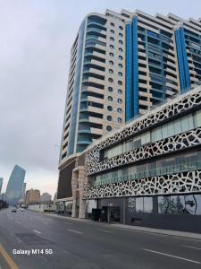 a large building with a white walkway next to a street at Vip Apartment Azure Tower in Baku