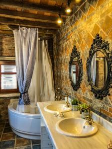 een badkamer met 2 wastafels, een bad en 2 spiegels bij Lykos Mansion in Kápsas