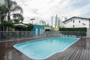 a large blue swimming pool on a wooden deck at Apto em Barra Velha 340m da PRAIA com SACADA com CHURRASQUEIRA, AR CONDICIONADO WI-FI, PISCINA, PORTARIA 24h, ACADEMIA MINI MERCADO e vaga de GARAGEM in Barra Velha +18 photos