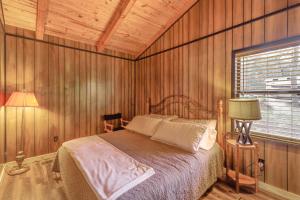 a bedroom with a bed in a room with wooden walls at Rustic Waterfront Getaway on Greers Ferry Lake! in Fairfield Bay