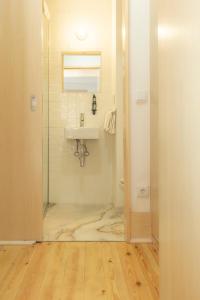 a bathroom with a sink and a glass door at Vinum Apartamentos 1890 in Coimbra