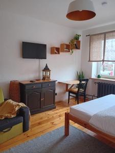 a bedroom with a bed and a desk with a tv at Daugavas apartamenti in Ogre