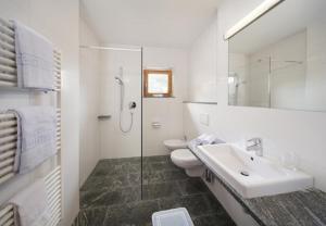 een witte badkamer met een wastafel en een toilet bij Hotel Edelweiss in Malles Venosta