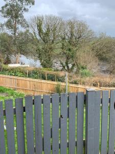 a white picket fence in front of a field at Cosy 2 bedroom Cottage in Saint Dogmaels- river views in Cardigan