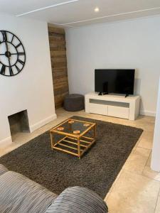 sala de estar con reloj en la pared y TV en Cosy 2 bedroom Cottage in Saint Dogmaels- river views, en Cardigan