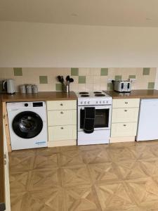 a kitchen with a stove and a washing machine at Cosy 2 bedroom Cottage in Saint Dogmaels- river views in Cardigan