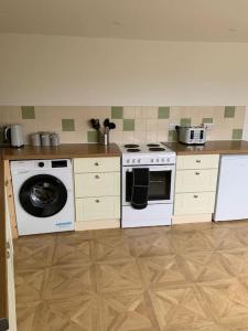a kitchen with a stove and a washing machine at Bryndegwel in Saint Dogmaels, cardigan- river views, Free parking in Cardigan