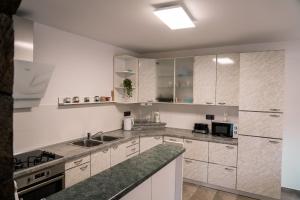una cocina con armarios blancos y fregadero en Apartma Ksela, en Mala Nedelja