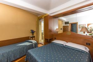 a bedroom with two beds and a mirror at Hotel Mondial in Lido di Jesolo