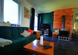 een woonkamer met een groene bank en een open haard bij Dom w lesie in Łukta