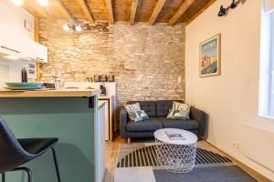 een keuken en een woonkamer met een bank en een tafel bij L'alouette - Duplex Climatisé & Authentique in Castres