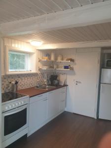 a kitchen with white cabinets and a stove top oven at Hyttan in Åkirkeby