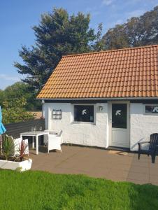 a white house with a table and chairs in a yard at Hyttan in Åkirkeby