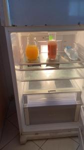 een open koelkast met twee potten sinaasappelsap bij HAVRE DE PAIX in Le Robert