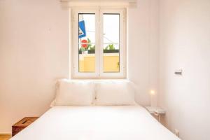 a white bed in a room with a window at Vila Margarida Beach Haven in Estoril